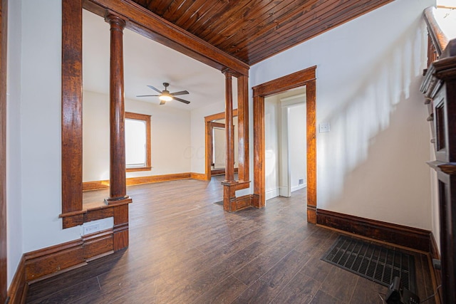 living room featuring dark wood-type flooring, ceiling fan, decorative columns, and wooden ceiling