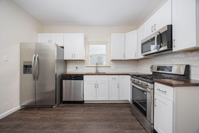 kitchen with appliances with stainless steel finishes, dark hardwood / wood-style floors, sink, and white cabinets