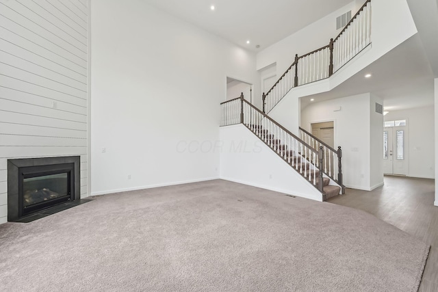 unfurnished living room with a towering ceiling and dark carpet