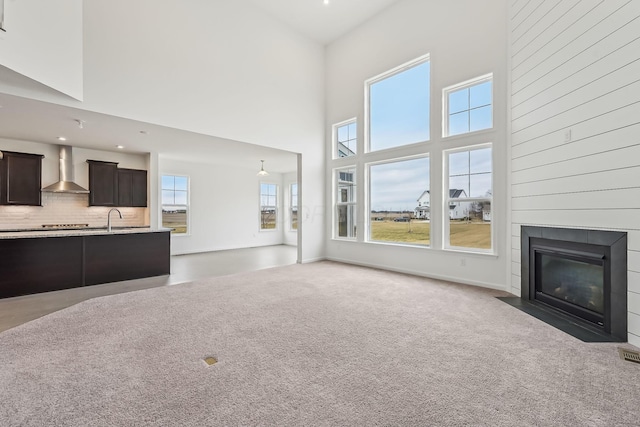 unfurnished living room with sink, a high ceiling, and dark colored carpet