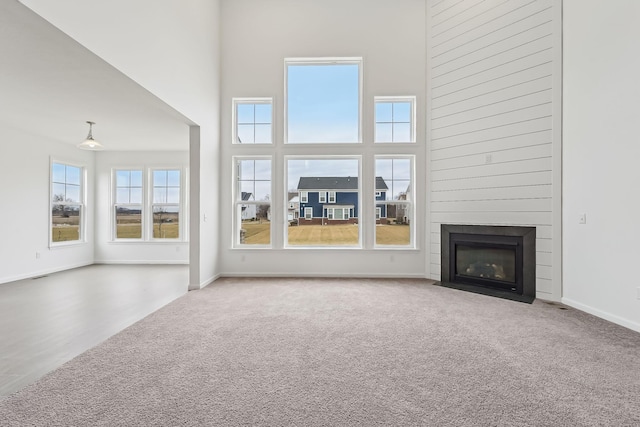 unfurnished living room featuring carpet flooring, a fireplace, and a high ceiling