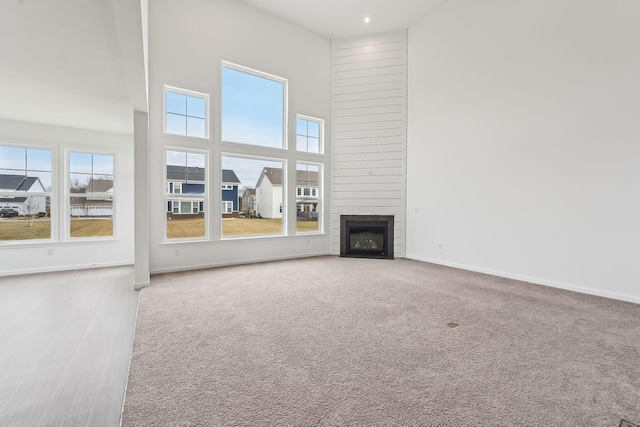 unfurnished living room featuring a towering ceiling, carpet flooring, and a large fireplace