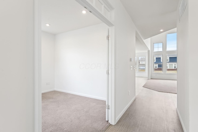 corridor featuring light carpet and vaulted ceiling