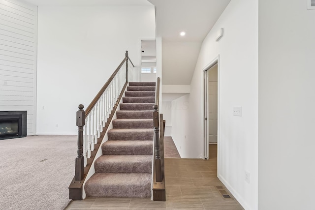 stairway featuring carpet floors and a fireplace