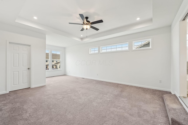 carpeted empty room with a raised ceiling and ceiling fan