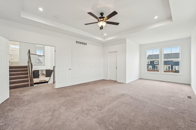 interior space featuring ceiling fan, a raised ceiling, and carpet floors