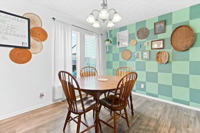 dining space with wood-type flooring, a chandelier, and a textured ceiling