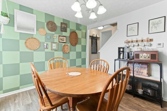 dining area with wood-type flooring, a chandelier, and a textured ceiling