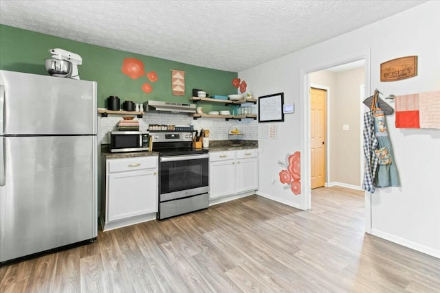 kitchen with a textured ceiling, tasteful backsplash, white cabinetry, light wood-type flooring, and stainless steel appliances