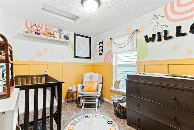 bedroom featuring a nursery area and a textured ceiling