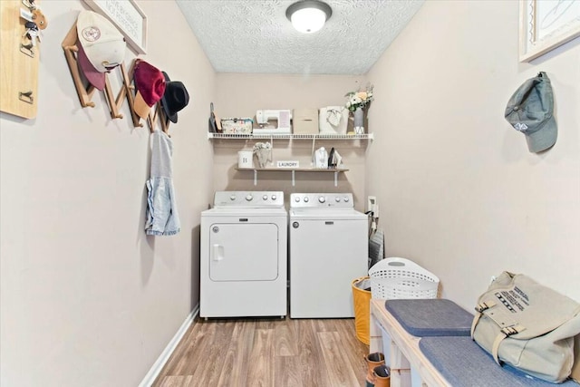 washroom featuring independent washer and dryer, light wood-type flooring, and a textured ceiling