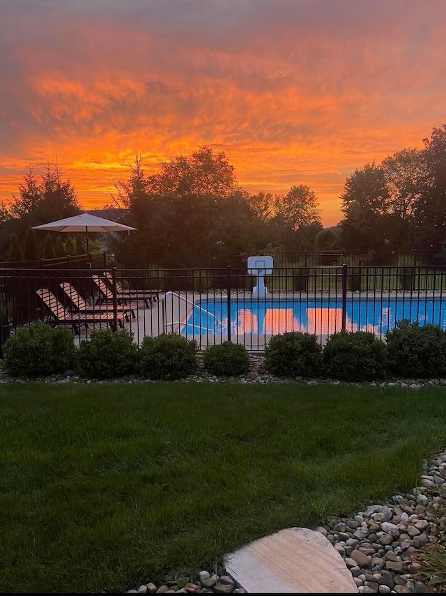 pool at dusk featuring a yard