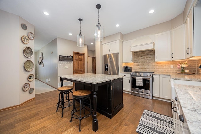 kitchen featuring high end appliances, a kitchen island, white cabinets, and premium range hood