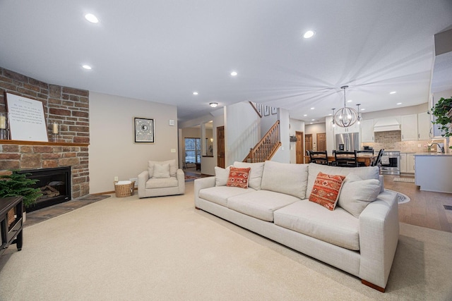 living room with sink, a chandelier, a fireplace, and light hardwood / wood-style floors