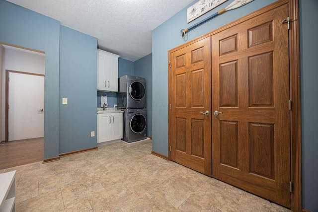 washroom with cabinets, stacked washer and clothes dryer, and a textured ceiling