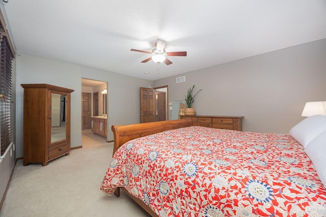 bedroom with light carpet, connected bathroom, and ceiling fan