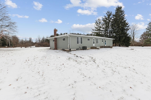 snow covered rear of property featuring central AC