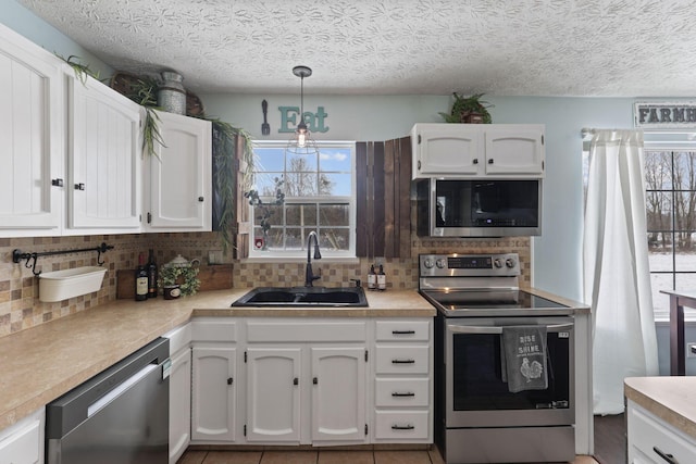 kitchen featuring sink, tasteful backsplash, appliances with stainless steel finishes, pendant lighting, and white cabinets