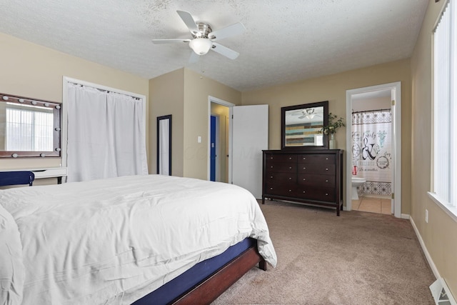 carpeted bedroom featuring ceiling fan, ensuite bath, and a textured ceiling