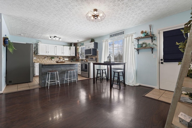 kitchen featuring a kitchen bar, white cabinetry, tasteful backsplash, appliances with stainless steel finishes, and dark hardwood / wood-style floors