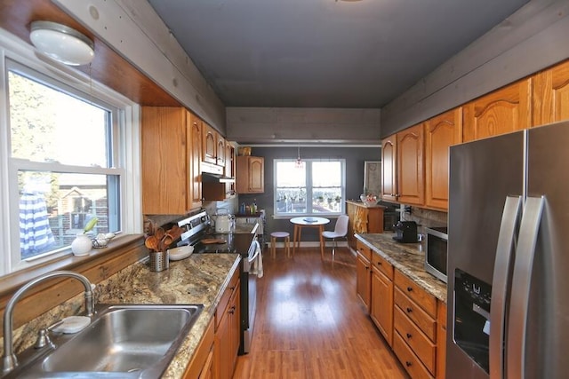 kitchen with sink, light hardwood / wood-style flooring, stainless steel appliances, and light stone countertops