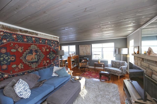 living room featuring hardwood / wood-style flooring, ornamental molding, a stone fireplace, and wooden ceiling