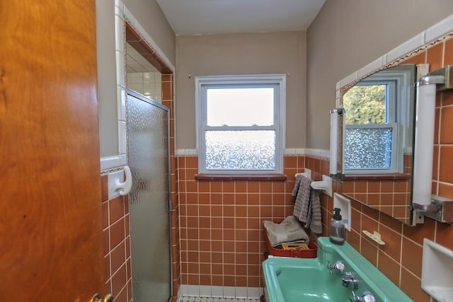 bathroom with a wealth of natural light, tile walls, and a shower with shower door