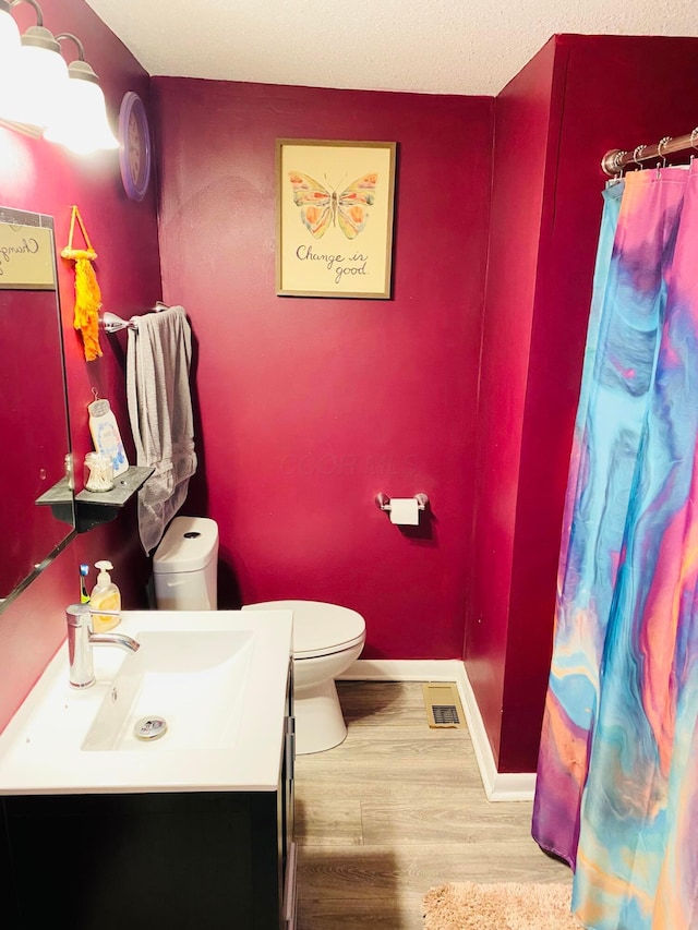 bathroom with hardwood / wood-style flooring, toilet, and vanity