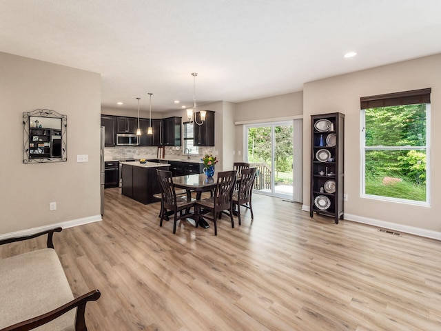 dining space with sink, light hardwood / wood-style floors, and an inviting chandelier