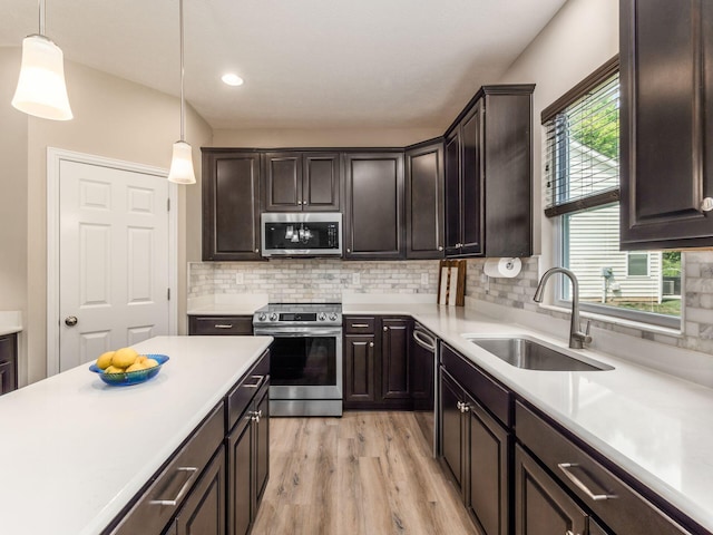 kitchen with decorative light fixtures, sink, appliances with stainless steel finishes, and dark brown cabinets