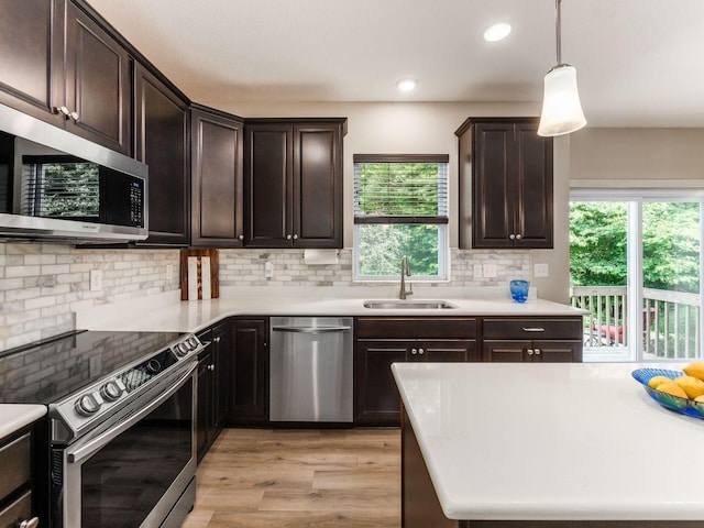 kitchen featuring backsplash, sink, pendant lighting, and appliances with stainless steel finishes