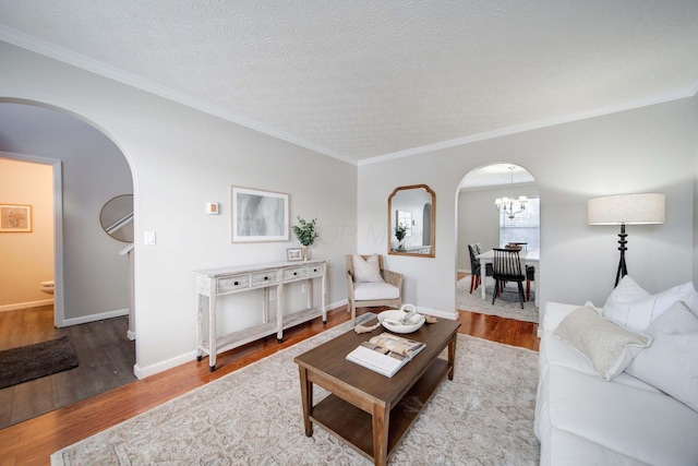 living room featuring crown molding, light wood-type flooring, an inviting chandelier, and a textured ceiling