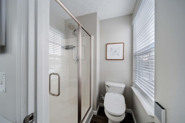 bathroom featuring toilet, a textured ceiling, and a shower with shower door