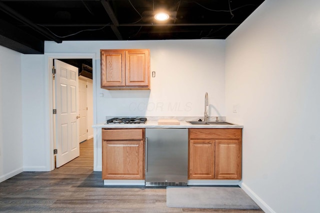 kitchen with wood-type flooring, fridge, sink, and stainless steel gas cooktop