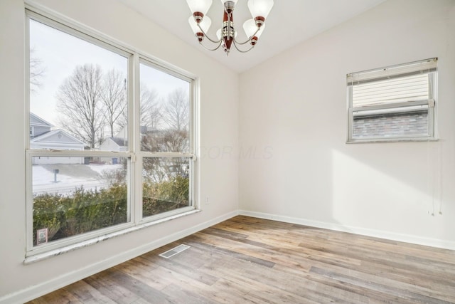 empty room with a chandelier and light wood-type flooring