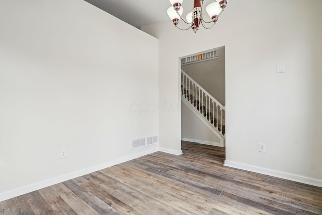 empty room featuring hardwood / wood-style floors and a chandelier