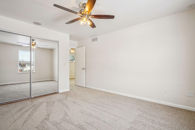 unfurnished bedroom with light colored carpet, a closet, and ceiling fan