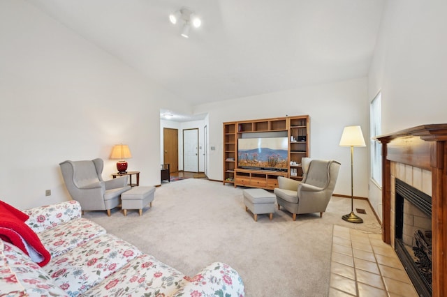 carpeted living room featuring a tile fireplace and vaulted ceiling