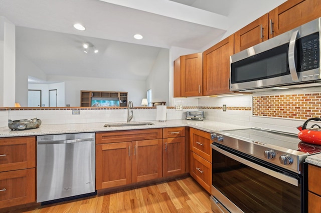 kitchen with vaulted ceiling, tasteful backsplash, sink, stainless steel appliances, and light stone countertops