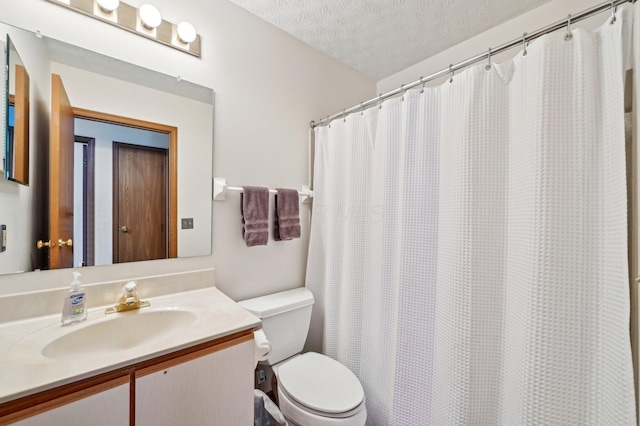 bathroom with vanity, toilet, curtained shower, and a textured ceiling