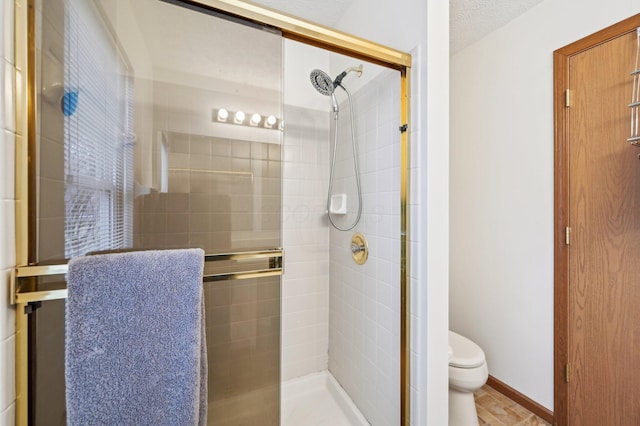 bathroom with toilet, an enclosed shower, and a textured ceiling