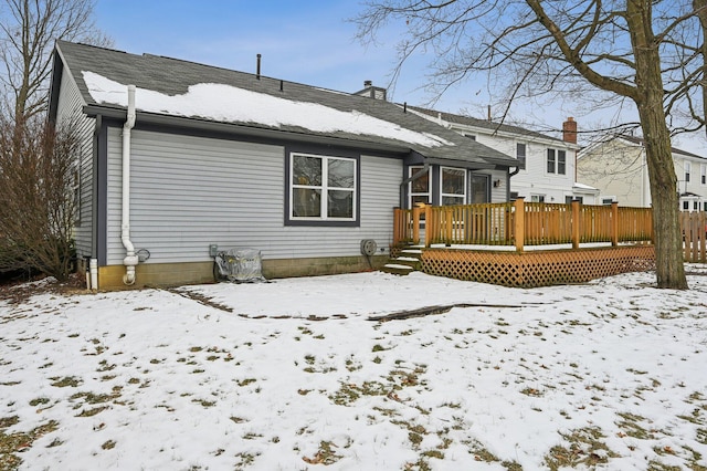 snow covered back of property featuring a wooden deck