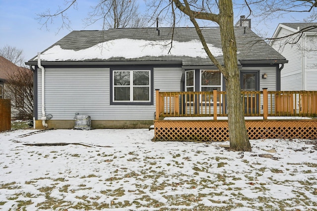 snow covered rear of property with a wooden deck