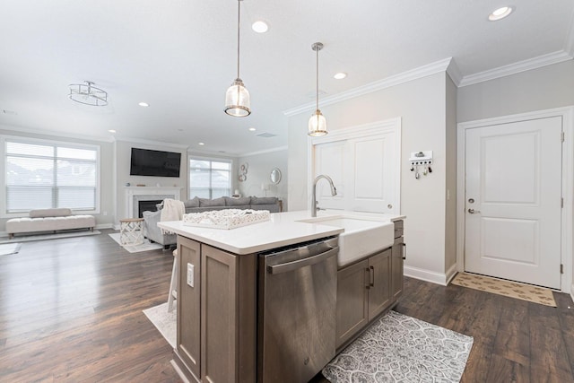 kitchen featuring decorative light fixtures, sink, stainless steel dishwasher, crown molding, and a center island with sink