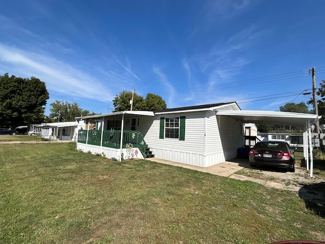 manufactured / mobile home featuring a front lawn, a carport, and covered porch