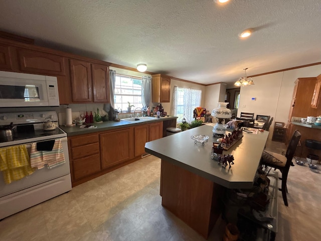 kitchen featuring a kitchen bar, sink, crown molding, a center island, and white appliances