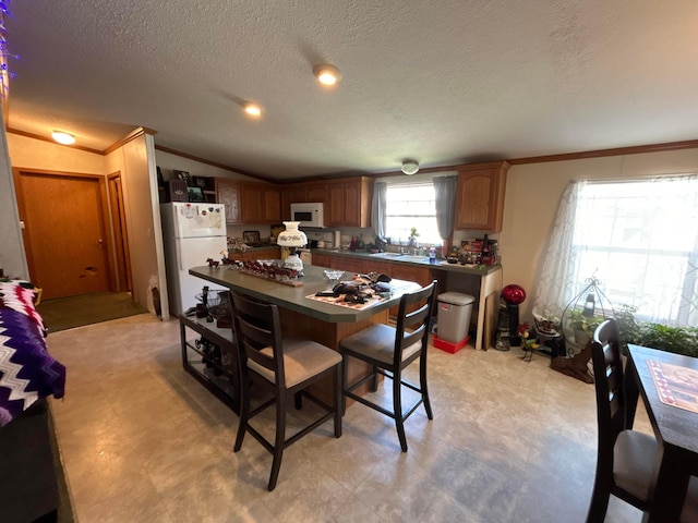 kitchen featuring lofted ceiling, sink, white appliances, crown molding, and a textured ceiling