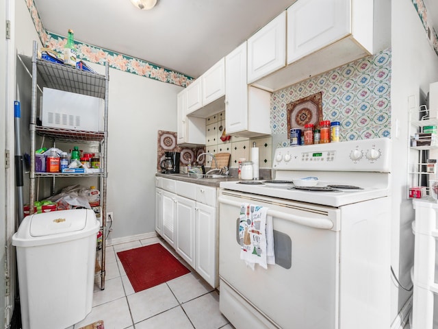 kitchen with light tile patterned floors, decorative backsplash, white cabinets, white range with electric stovetop, and sink