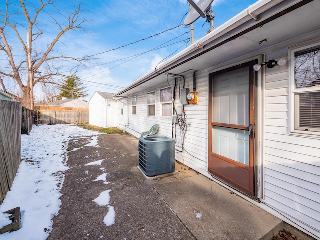 snowy yard featuring central AC unit and a patio area