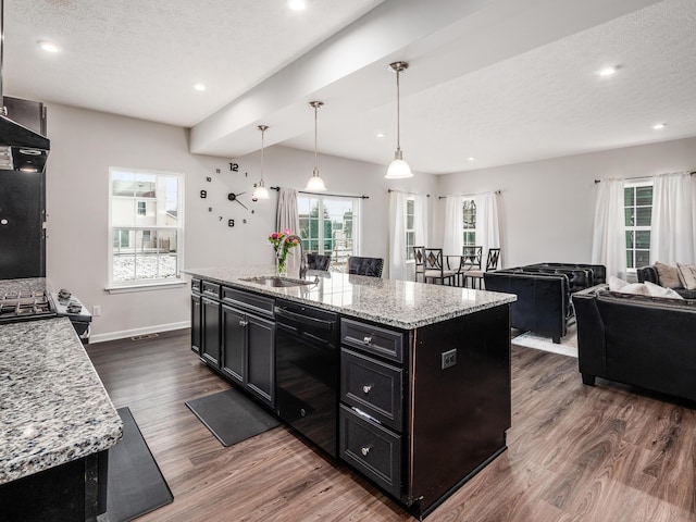 kitchen with dishwasher, decorative light fixtures, sink, light stone counters, and a center island with sink